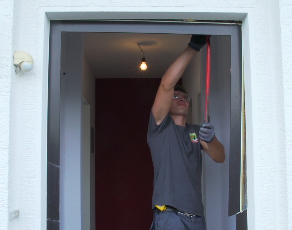 Zwei Handwerker entfernen den Haustürflügel 