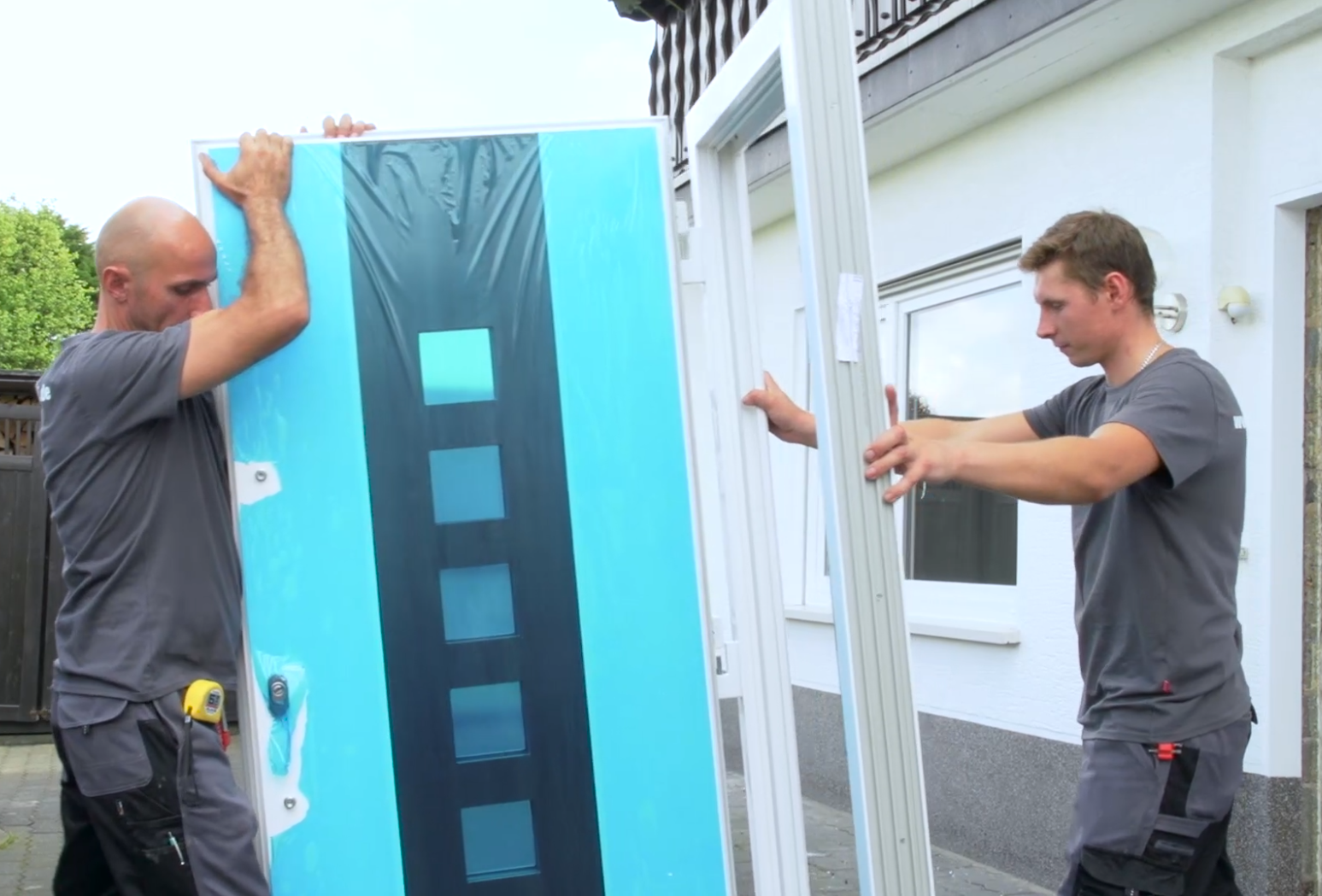 Zwei Handwerker entfernen den Haustürflügel 